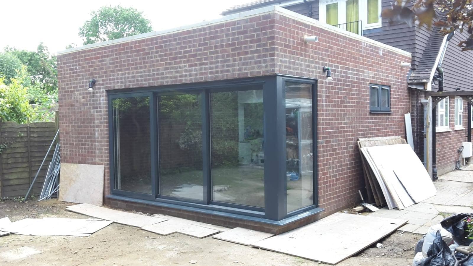 A finished single-storey extension by Trojan Construction with full-width anthracite-grey bifold doors